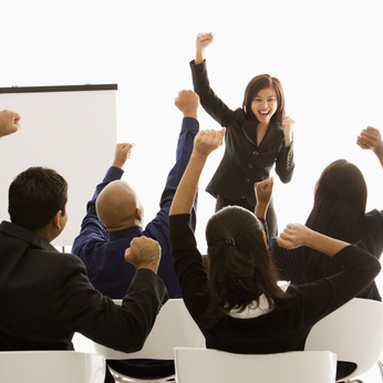 businesswoman leading presentation while audience cheers.